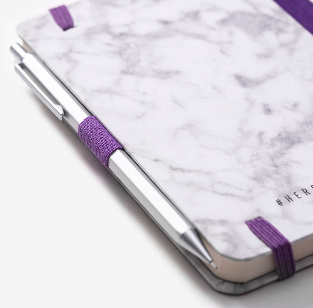 Marble printed notebook with purple elastic pen loop holding chrome metal pen