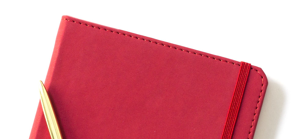 Red faux leather Notebook with a matching perimeter stitching, elastic band and a gold metal pen