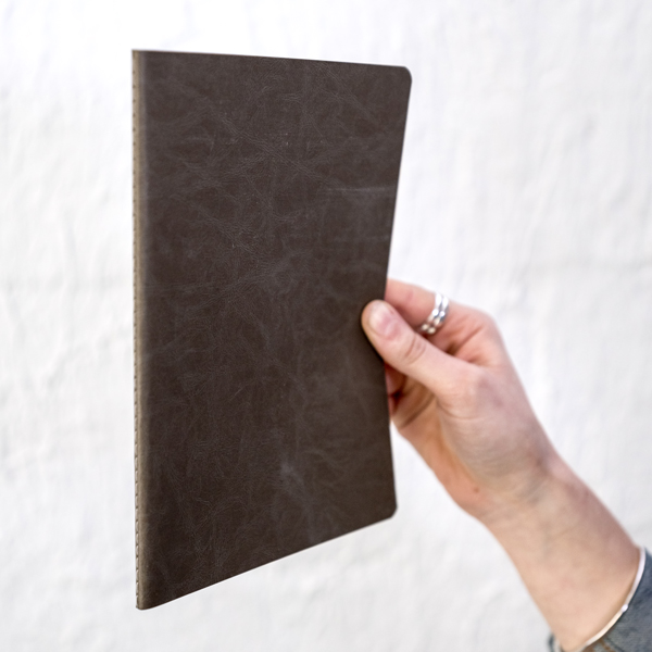 hand holding black singer-sewn softcover journal