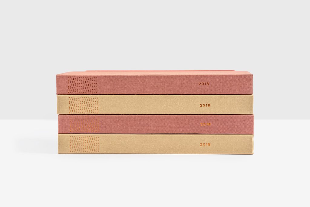 Pile of four pink and beige Ponderlilly clothbound hardcover planners with copper foiling on the spine