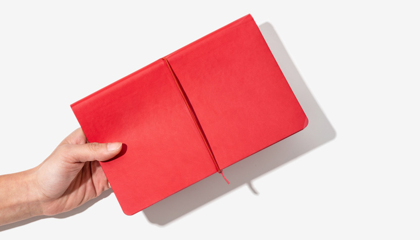 Hand holding a softcover A5 notebook - horizon notebook softcover with horizontal elastic Hand holding a softcover A5 notebook - horizon notebook softcover with horizontal elastic