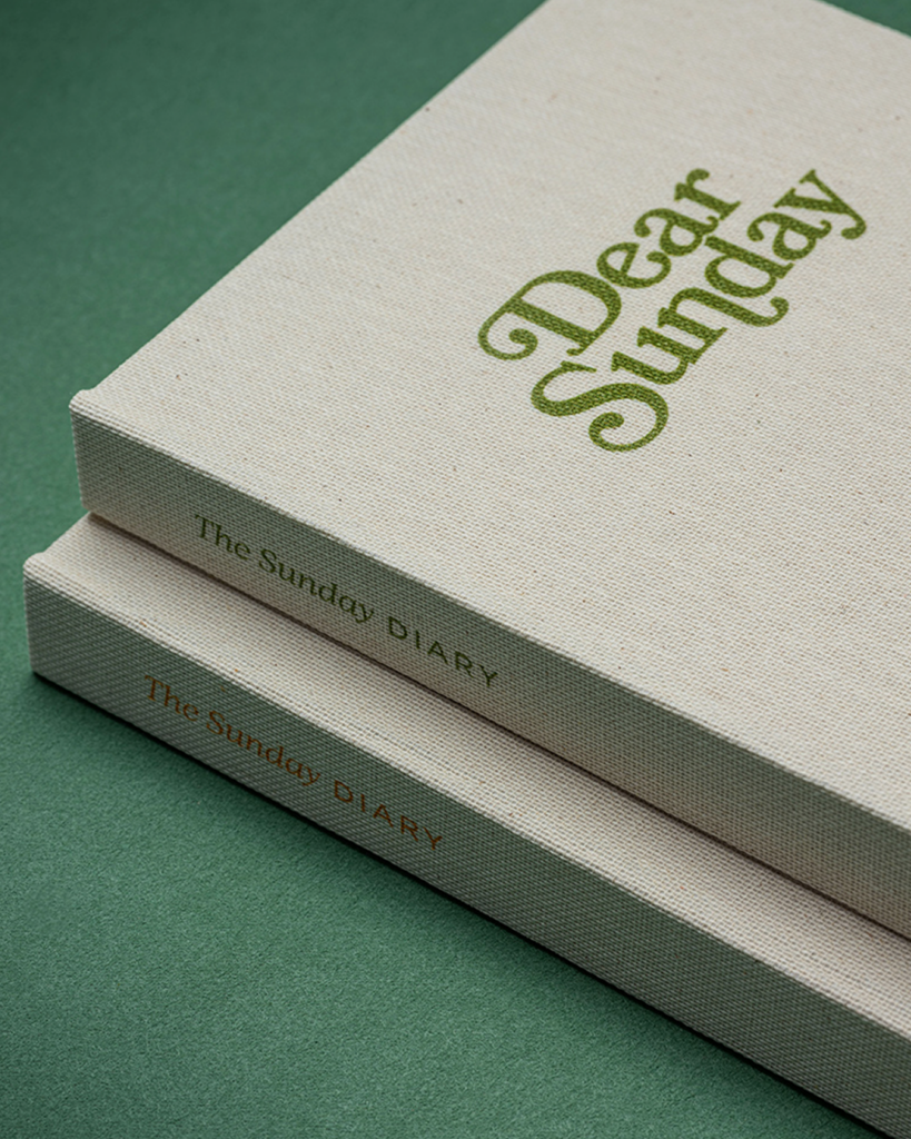 A set of two linen cloth notebooks with red and green UV printed branding for dear sunday planners